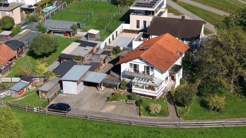 Luftaufnahme des Anwesens mit Wohnhaus, Nebengebäuden und umliegender grüner Landschaft.