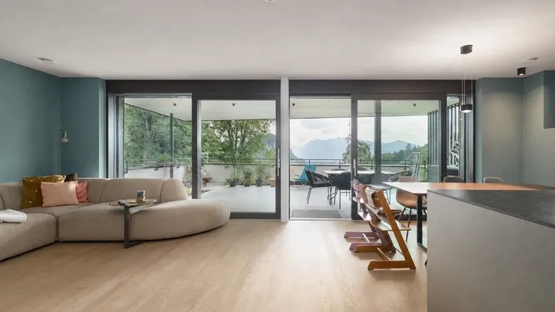 Heller Wohn- und Essbereich mit Holzboden, Zugang zur Terrasse und Bergblick.