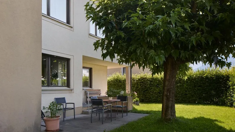 Gepflasterte Terrasse mit Gartenmöbeln und Rasenfläche neben dem Haus.
