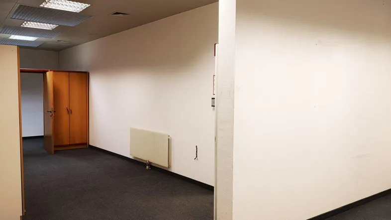 Geräumiger Bürobereich mit Teppichboden, Heizkörpern und abgehängter Decke, bereit zur individuellen Gestaltung.