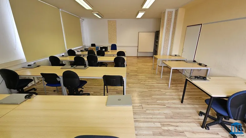 Geräumiger Büroraum mit mehreren Schreibtischen, Bürostühlen und hellem Laminatboden, ideal für Schulungen oder Arbeitsgruppen.