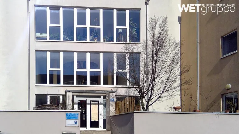 Moderne Fassade eines Gebäudes mit großen, strukturierten Fenstern und klaren Linien.
