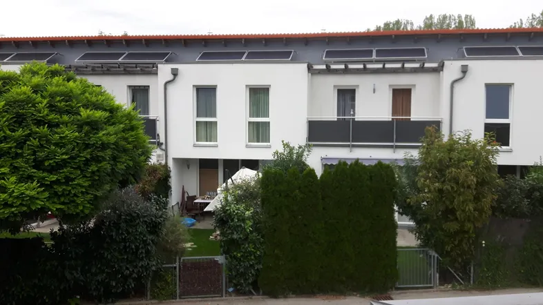 Reihenhäuser mit moderner Architektur, Photovoltaikanlage auf dem Dach und privaten Gärten.