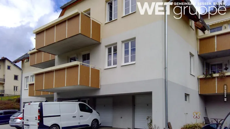 Mehrfamilienhaus mit mehreren Balkonen, integrierten Garagen und einer hellen Fassade.