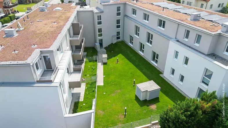 Moderne Wohnanlage mit begrünten Dächern, Balkonen und einem grünen Innenhof.