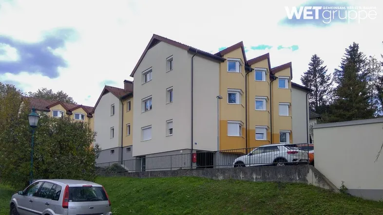 Gut erhaltenes Mehrfamilienhaus mit Satteldach, hellen Fassaden und Rollläden in ländlicher Umgebung.