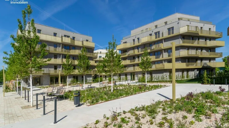 Moderne Wohngebäude mit Balkonen und gepflegten Außenanlagen unter blauem Himmel.