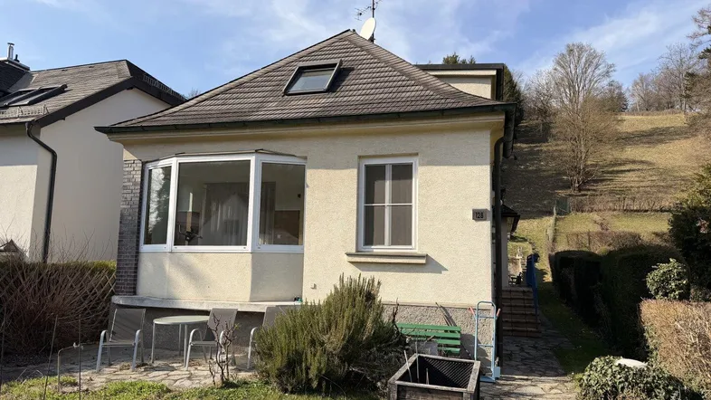 Kleines Einfamilienhaus mit Erker, Satteldach und Gartenbereich in sonniger Hanglage.