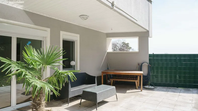 Überdachte Terrasse mit Sitzgelegenheiten und einer Palme, ideal zum Entspannen im Freien.