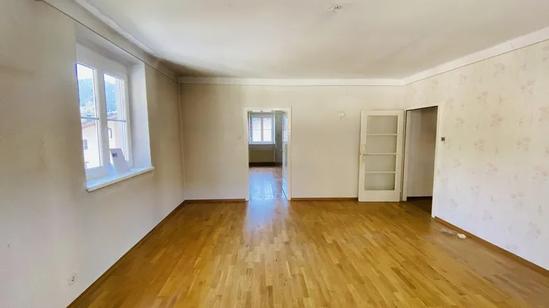 Geräumiges, leeres Zimmer mit Holzboden und Fenstern, bereit für die Renovierung.