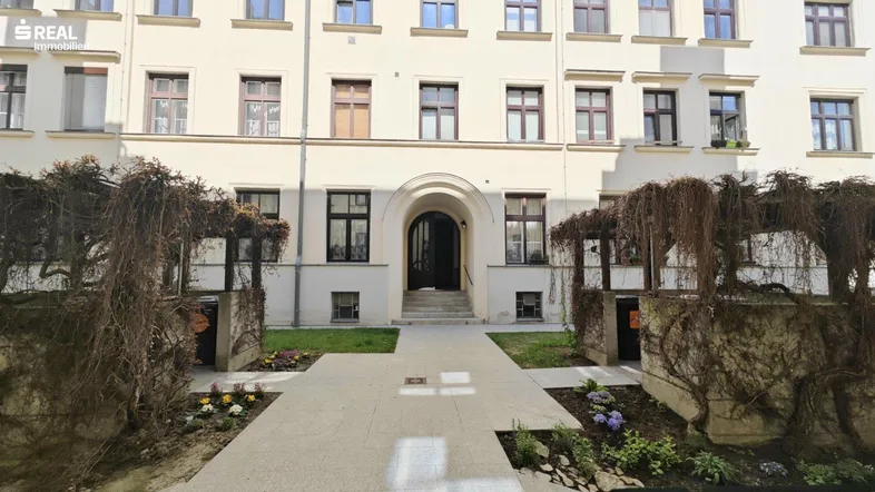 Eingangsbereich eines Mehrfamilienhauses mit gepflegtem Vorgarten und klassischer Architektur.