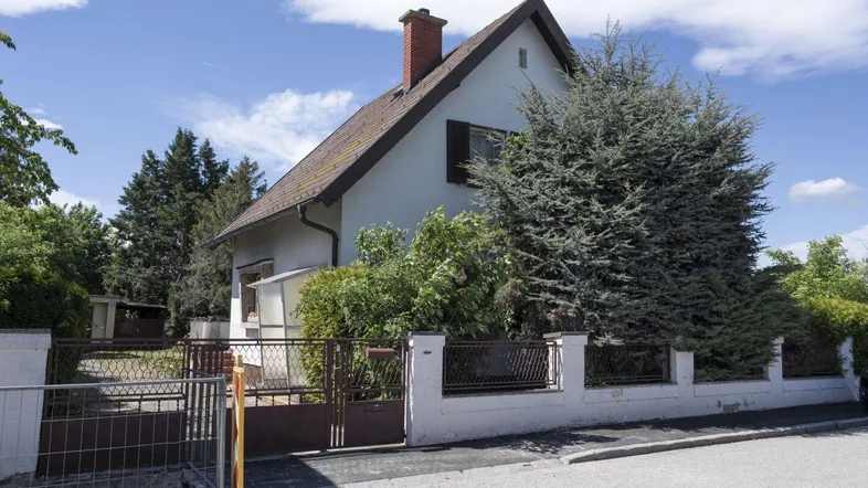 Freistehendes Einfamilienhaus mit Satteldach, umgeben von einem gepflegten Vorgarten und Zaun.