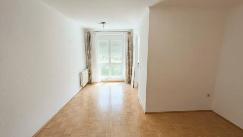 Helles, leeres Zimmer mit Parkettboden und großem Fenster, bereit zur individuellen Gestaltung.