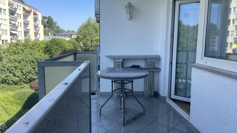 Heller Balkon mit Fliesenboden und kleinem Tisch, ideal für entspannte Stunden im Freien.