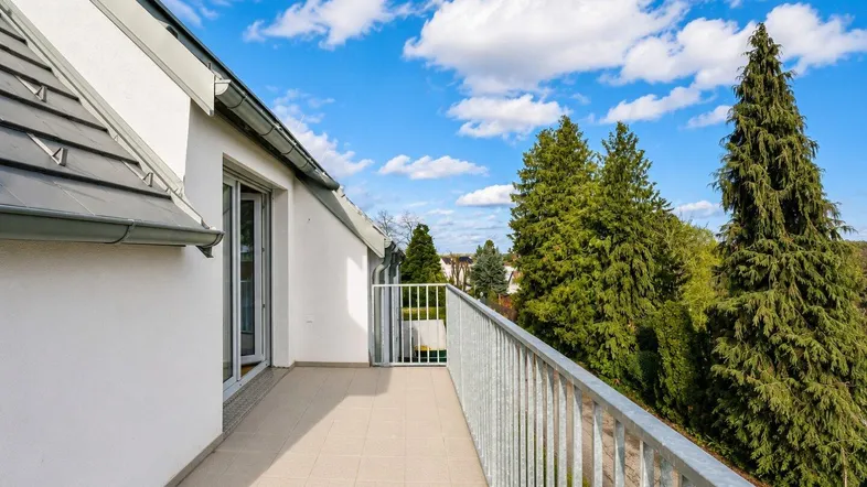 Heller Balkon mit Fliesenboden und Blick ins Grüne, ideal zum Entspannen im Freien.