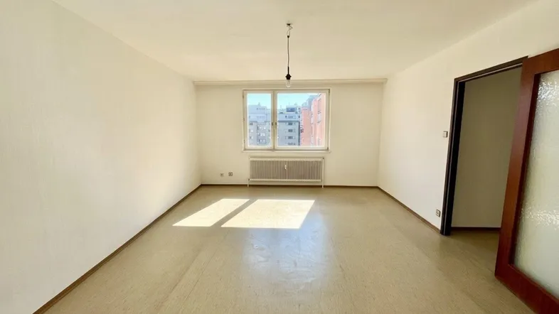 Helles, leeres Zimmer mit weiß gestrichenen Wänden und Blick auf die Stadt.