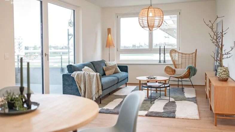 Helles Wohn- und Esszimmer mit modernem Sofa, Holzboden und Zugang zum Balkon.