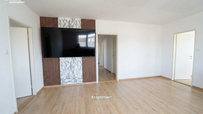 Helles Wohnzimmer mit modernem Wanddesign, Holzboden und Zugang zu weiteren Räumen.