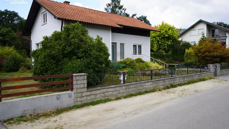 Ansicht des Einfamilienhauses von der Straße mit Vorgarten und Zaun.
