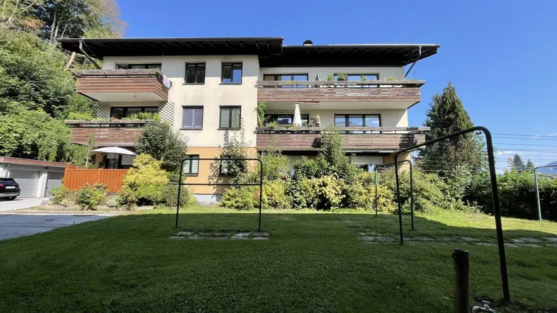 Mehrfamilienhaus mit mehreren Balkonen und einem gepflegten Gartenbereich in sonniger Lage.