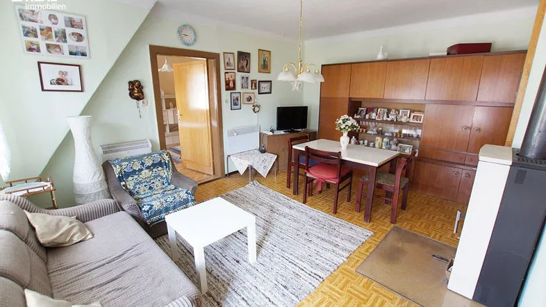 Gemütlicher Wohn-Essbereich mit Holzofen, Teppich und traditionellen Holzmöbeln.