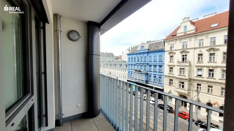 Balkon mit Blick auf die belebte Stadtstraße und historische Gebäude.
