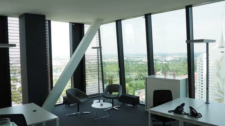 Modernes Büro mit großen Fenstern, die einen weiten Blick über die Stadt und die Landschaft bieten.