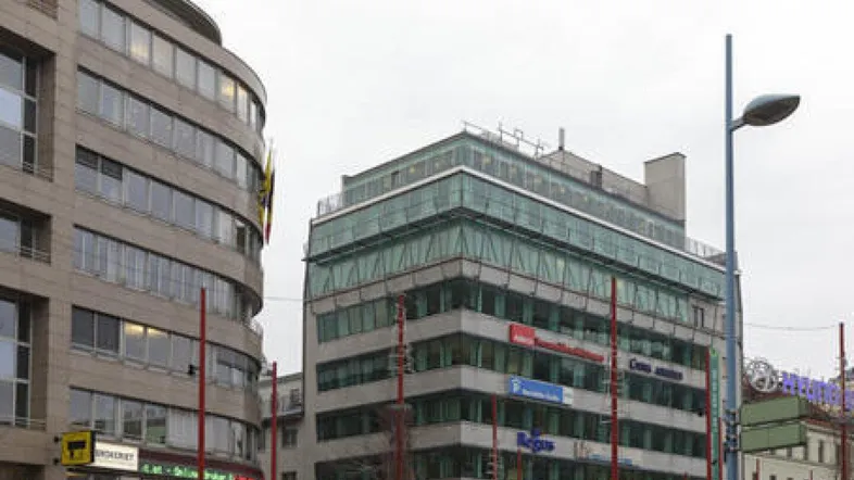 Moderne Bürogebäude mit Glasfassaden in einer städtischen Umgebung unter bewölktem Himmel.