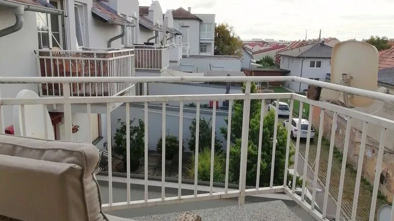 Möblierter Balkon mit Blick auf die umliegenden Gebäude und Dächer, ideal zum Entspannen.