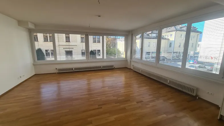 Helles, geräumiges Wohnzimmer mit Parkettboden und großen Fenstern, die viel Tageslicht hereinlassen.