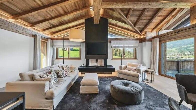 Helles Wohnzimmer mit Holzbalkendecke, modernem Kamin und Bergblick.