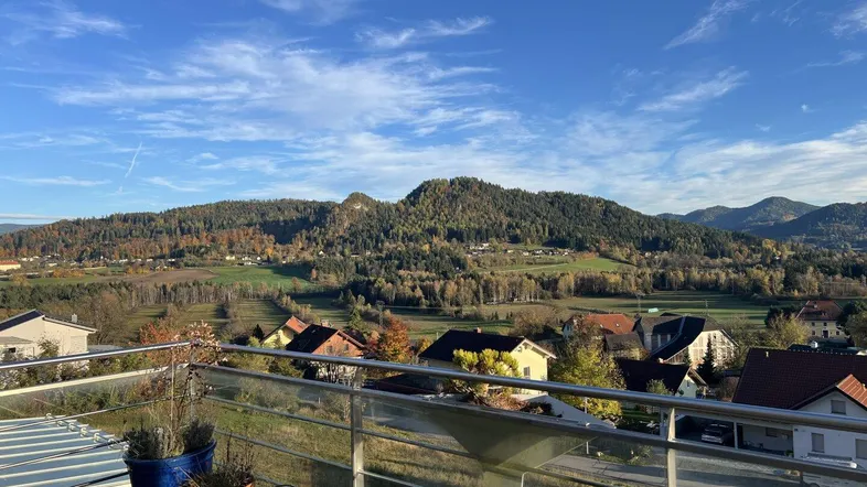 Balkon mit Glasgeländer und weitem Blick über die Landschaft und Berge.