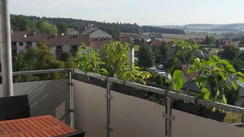 Heller Balkon mit Holzboden, Sitzgelegenheiten und weitem Blick über die Landschaft.