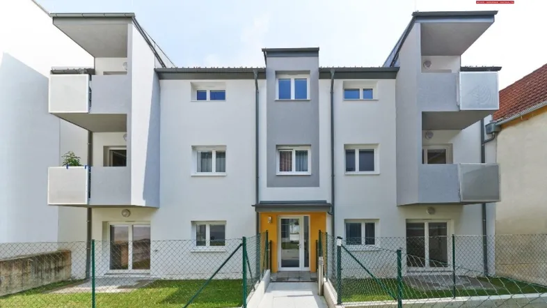 Modernes Mehrfamilienhaus mit Balkonen, Gartenanteil und gepflegter Fassade in heller Farbgebung.