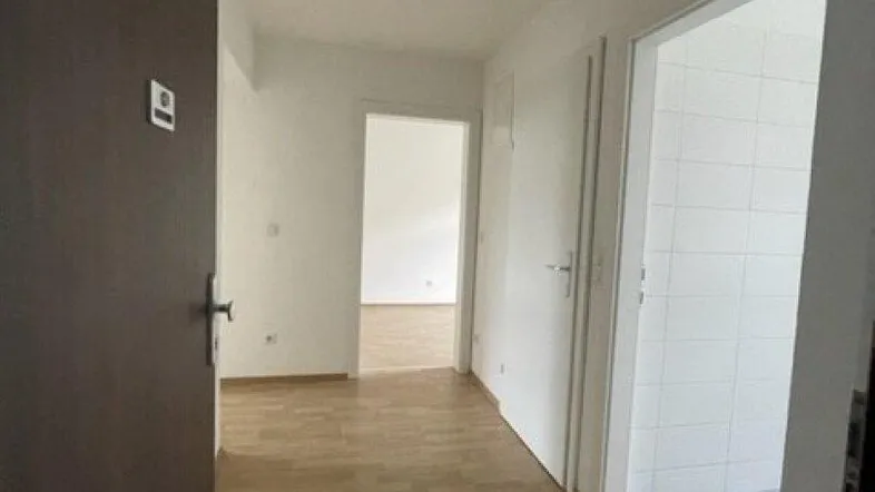 Heller Flur mit Holzboden und mehreren Türen, die zu den angrenzenden Räumen führen.