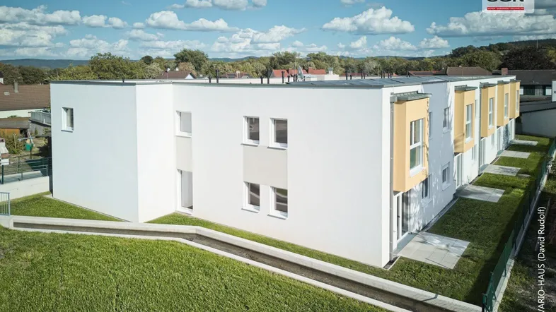 Seitenansicht der modernen Wohnanlage mit flachem Dach und gepflegten Rasenflächen.