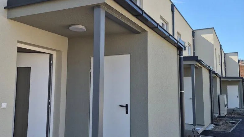 Reihenhäuser mit modernen Fassaden und überdachten Eingangsbereichen in einer neuen Siedlung.