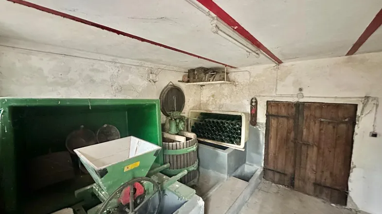 Alter Kellerraum mit Weinpresse und Flaschenlager, ideal für Weinliebhaber und Lagerung.