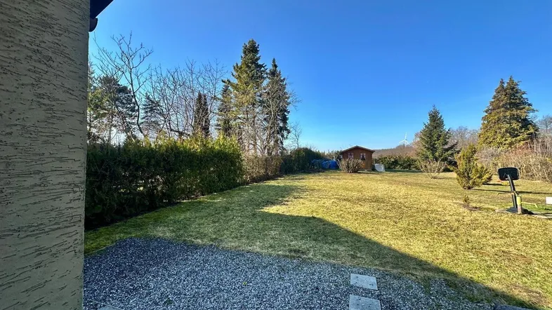 Großer Garten mit Rasenfläche, Bäumen und einem kleinen Gartenhaus im Hintergrund.