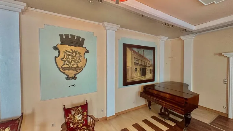 Geräumiger Wohnbereich mit Holzboden, Klavier und dekorativen Wandgemälden in einem traditionellen Ambiente.