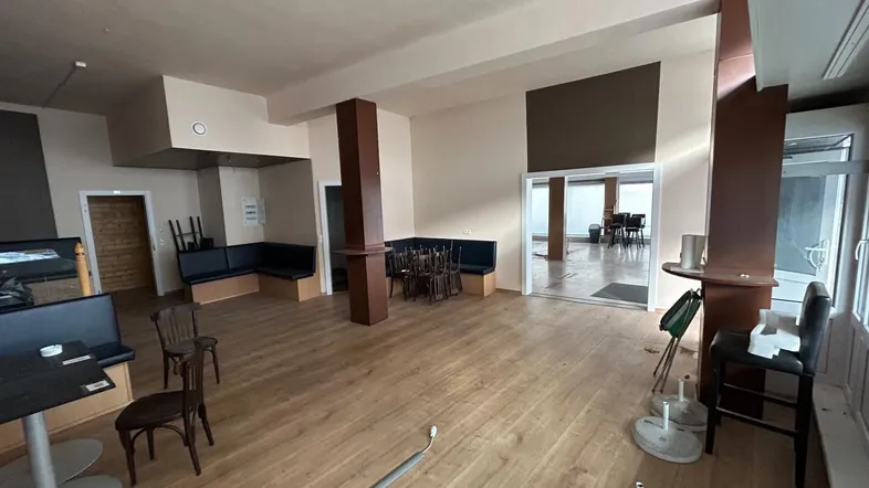 Geräumiger Gewerberaum mit Holzboden, Sitzbänken und Tischen, bereit für die Neugestaltung.