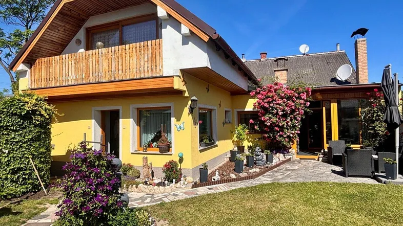 Gelbes Haus mit charmantem Garten, Balkon und gepflasterter Terrasse.