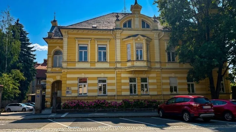 Historisches Gebäude mit auffälliger gelber Fassade und traditioneller Architektur, direkt an der Straße gelegen.