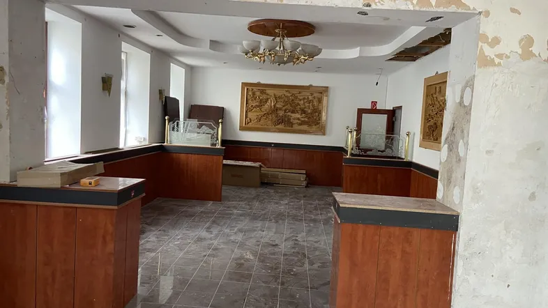 Innenraum in Renovierung mit abblätternder Farbe, Holzelementen und einer dekorativen Decke.