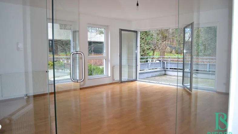 Helles Wohnzimmer mit Parkettboden und Zugang zu einer großzügigen Terrasse mit Blick ins Grüne.