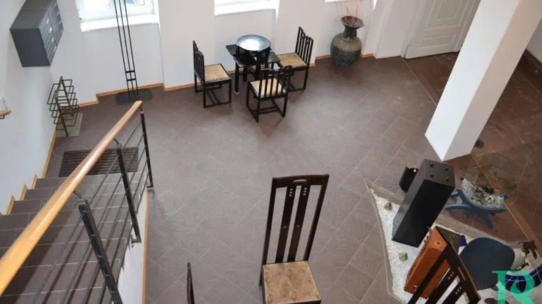 Geräumiger Eingangsbereich mit gefliestem Boden, Treppe und kleiner Sitzecke, von oben fotografiert.
