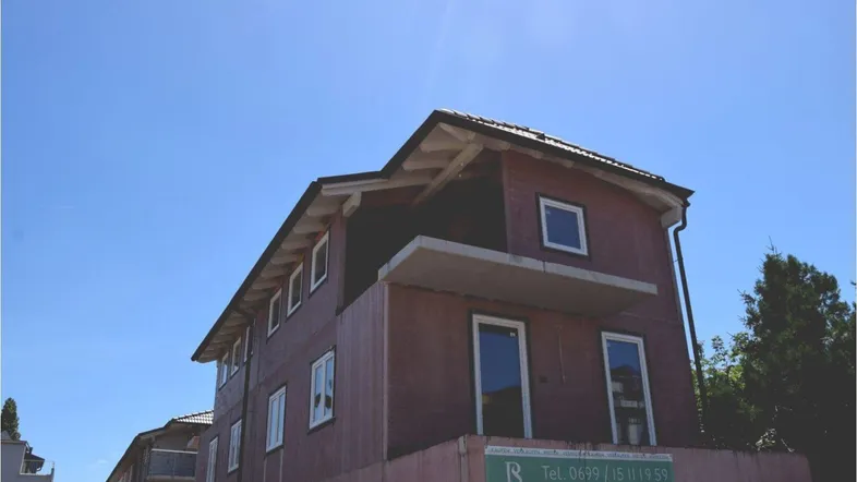 Das Gebäude befindet sich im Rohbau, mit sichtbaren Fenstern und einem zukünftigen Balkon.