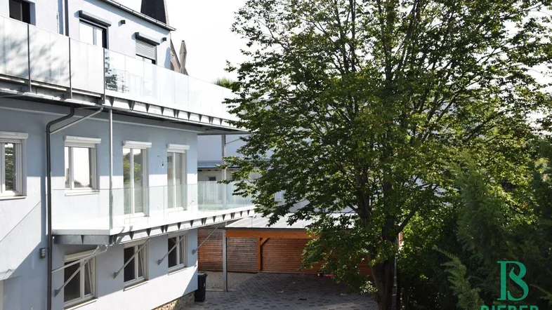 Ansicht der modernen Gebäudefassade mit Balkonen und einem Baum im Vordergrund.