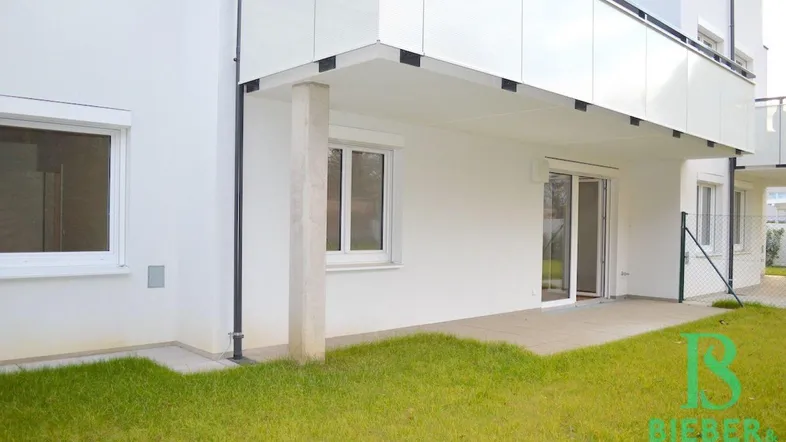 Erdgeschoss-Terrasse mit direktem Zugang zum Gartenbereich und Blick auf die moderne Fassade.
