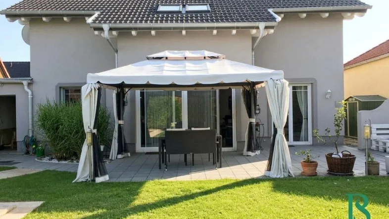 Hinteransicht eines Hauses mit gepflegtem Garten, Terrasse und einem Pavillon für gemütliche Stunden im Freien.